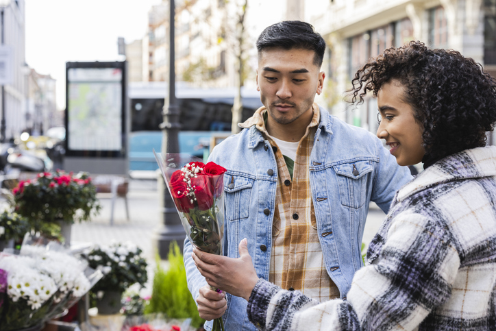 Young multiracial couple choosing red roses at flower market for valentine's day
