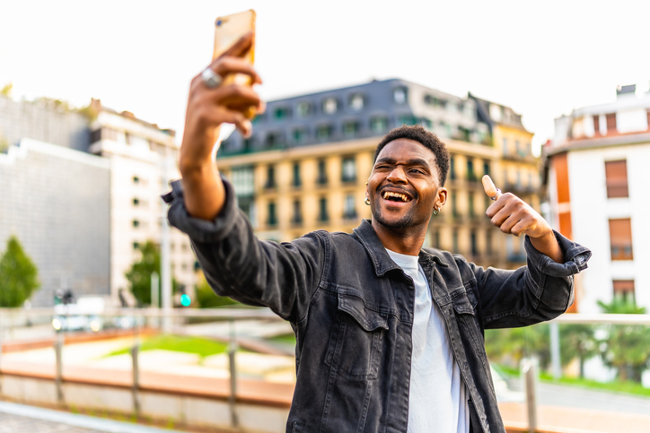 Cool african man winking while taking selfie in the city