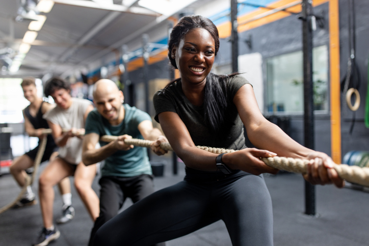 Fitness people playing tug of war challenge at cross training gym