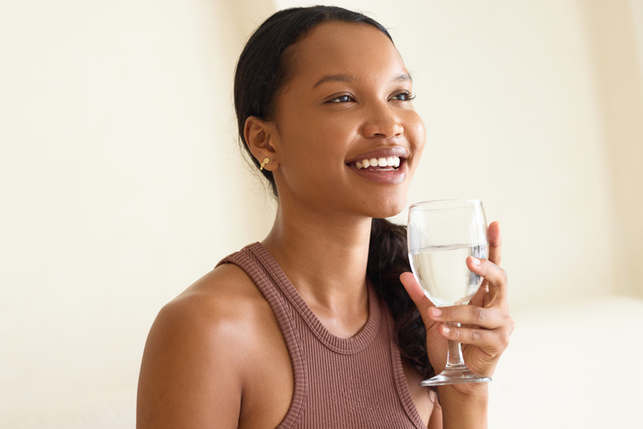 Hydration Joy: Woman Enjoying Fresh Glass of Water with Smile