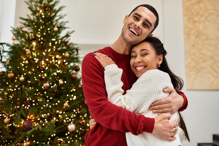 A loving couple enjoys cozy winter moments by a beautifully decorated tree