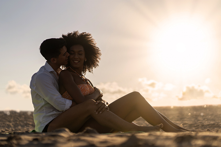 Romantic multiethnic couple hugging at sunset