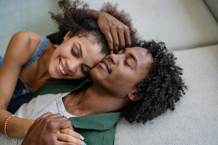 A young cheerful couple of African descent in a modern living room having an intimate moment of love and affection