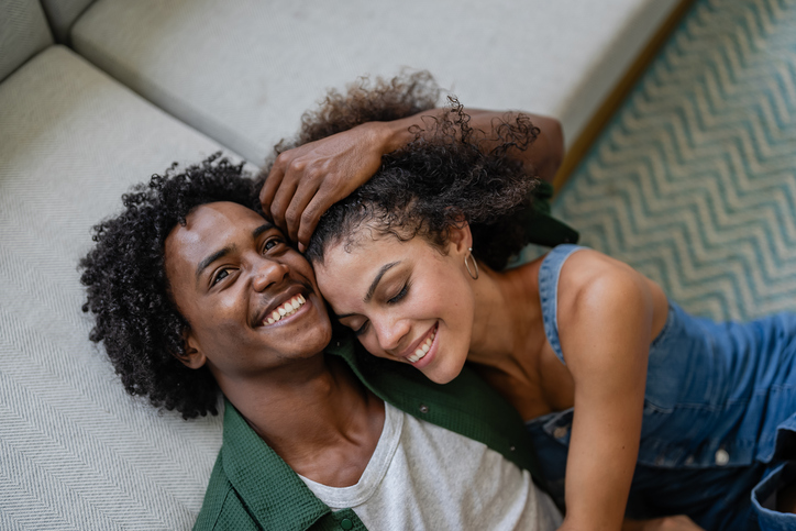 A young cheerful couple of African descent in a modern living room having an intimate moment of love and affection