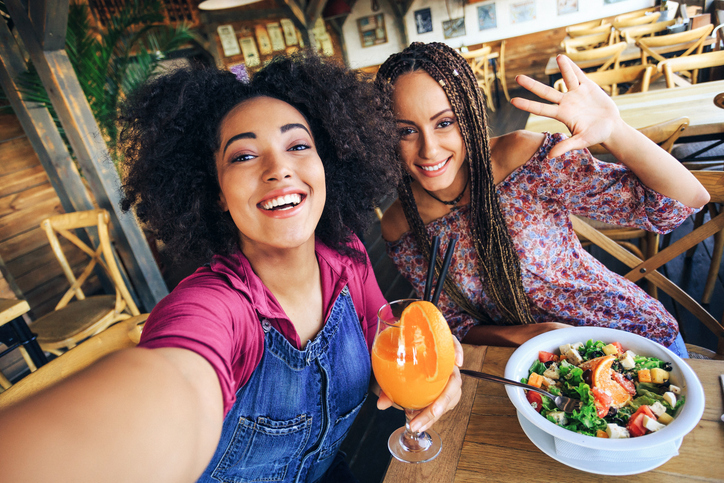 Young women in restaurant drinking juice and eating salad
