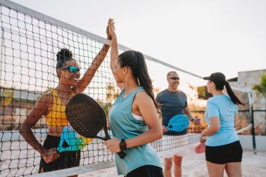Group of people shaking hands at the end of a beach tennis game