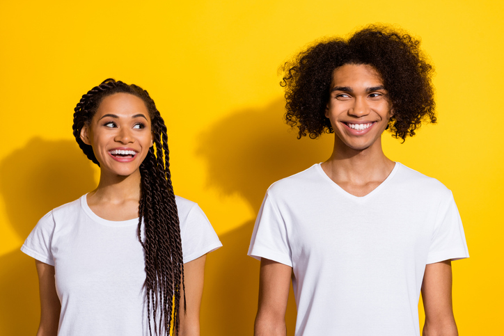 Photo of two cheerful positive people look interested each other toothy smile isolated on yellow color background