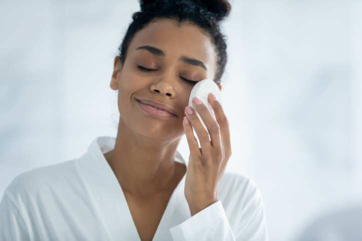 Happy relaxed Black girl cleaning facial skin from makeup