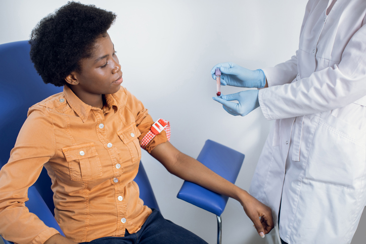 Healthy lifestyle, regular check up, blood analysis. Close up portrait of pretty young African woman, sitting in blue chair at modern lab. Lab technician nurse holding in hands test tube with blood.