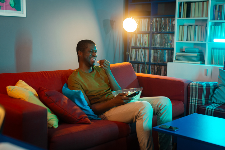Man watches television while enjoying popcorn in a cozy living room