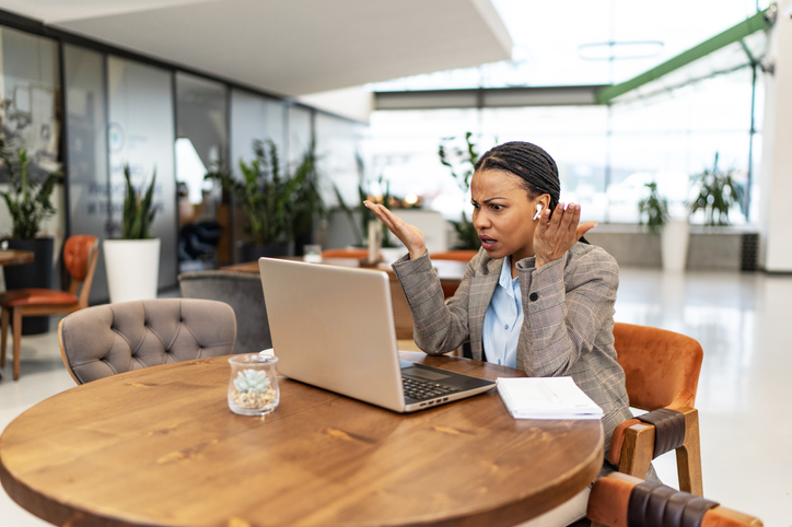 Frustrated businesswoman arguing with someone during a video call over computer