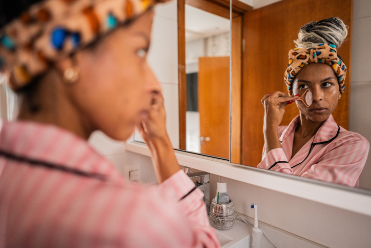 Mid adult woman doing skin care in front of a mirror in a bathroom