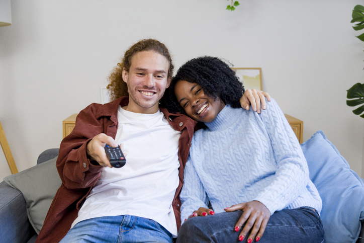 Happy couple watching tv and relaxing on sofa at home