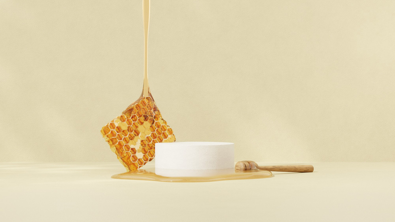 The display of honey products features a round wooden stand set against a yellow background, brightly illuminated by the morning sun.