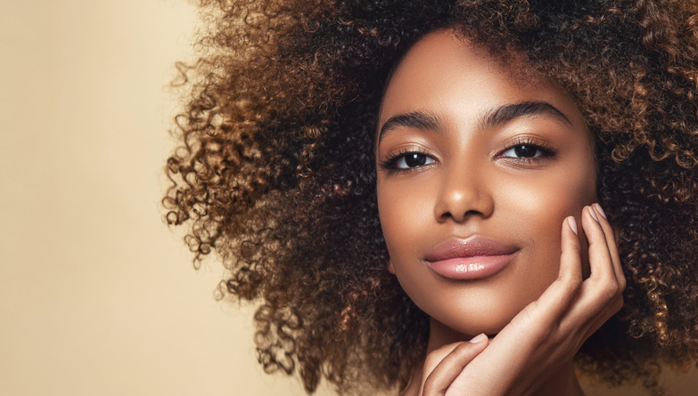 Sincere look and tender smile on the face of gorgeous young woman with melanin-rich skin tone woman. Natural Afro hair.