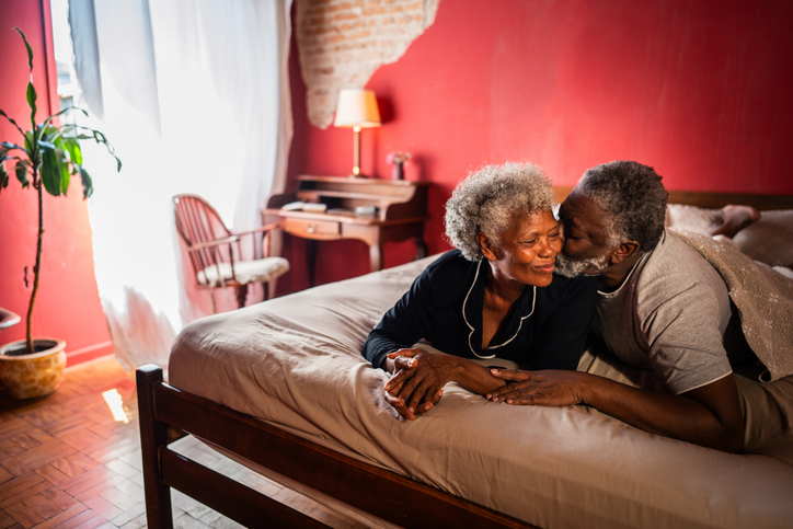 Husband kissing his wife on the cheeks in the bed at home