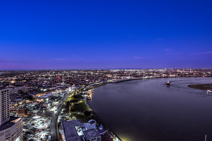 New Orleans ("Nola") "skyline" illuminated at dusk with Mississippi river in the foreground in New Orleans, Louisiana, USA