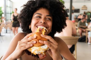 Happy young woman enjoying a delicious burger at a restaurant during summer vacation