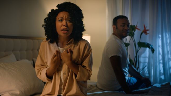 Couple family relationship problem conflict misunderstanding quarrel African American woman wife girlfriend angry mad husband boyfriend man sitting on bed night quarrelling screaming shouting arguing