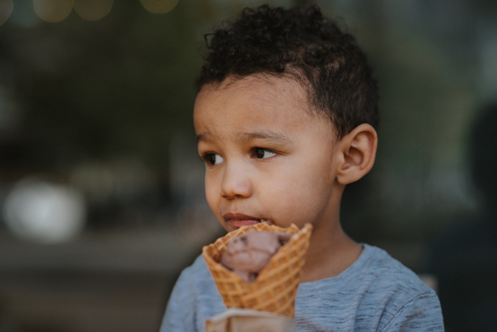 Multiracial toddler boy eating ice cream cone