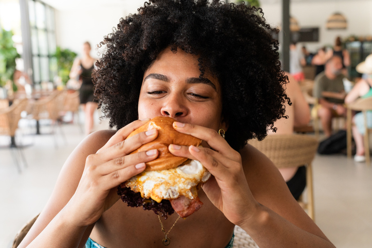 Young woman enjoying a delicious burger at a restaurant during summer vacation