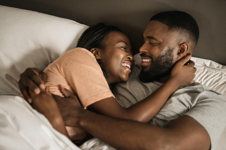 Young African American couple laughing together in bed