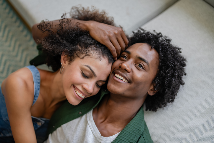 A young cheerful couple of African descent in a modern living room having an intimate moment of love and affection