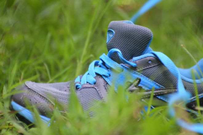 close up of a man putting a shoelace sitting on the green grass, Central Java, Indonesia