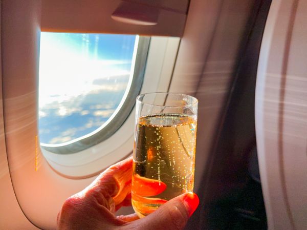 Person holding a glass of champagne in a business class cabin of a passenger jet