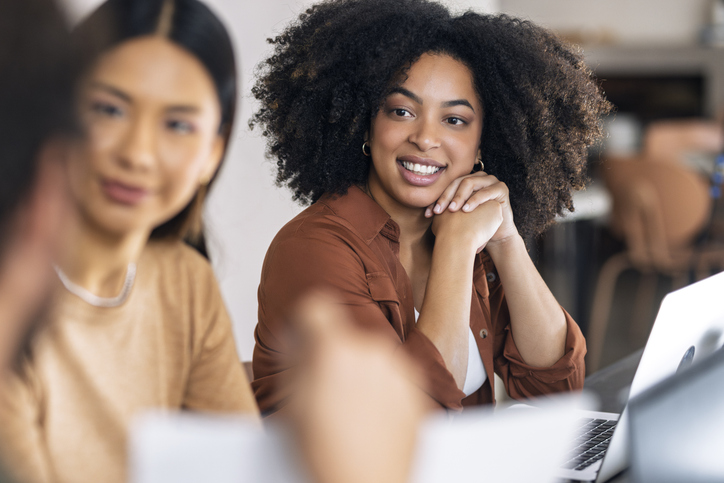 Businesswoman leaning on elbows and sitting at meeting in office