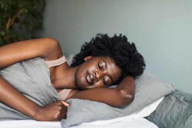 Young adult black woman sleeping in bedroom at home