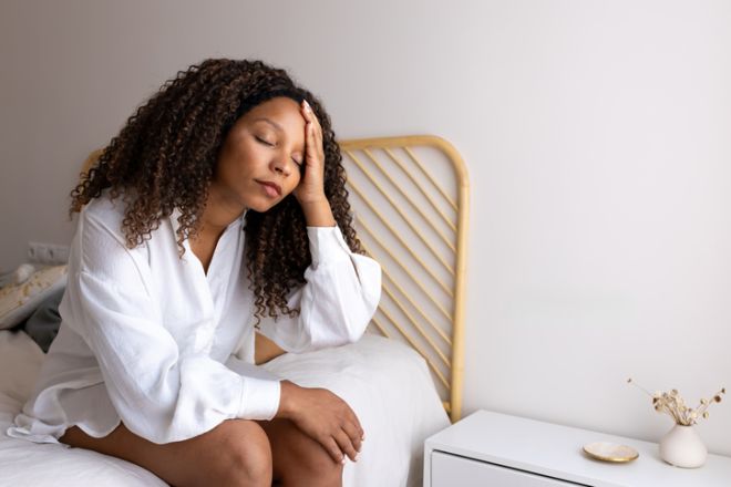 Young woman suffering from headache sitting on bed
