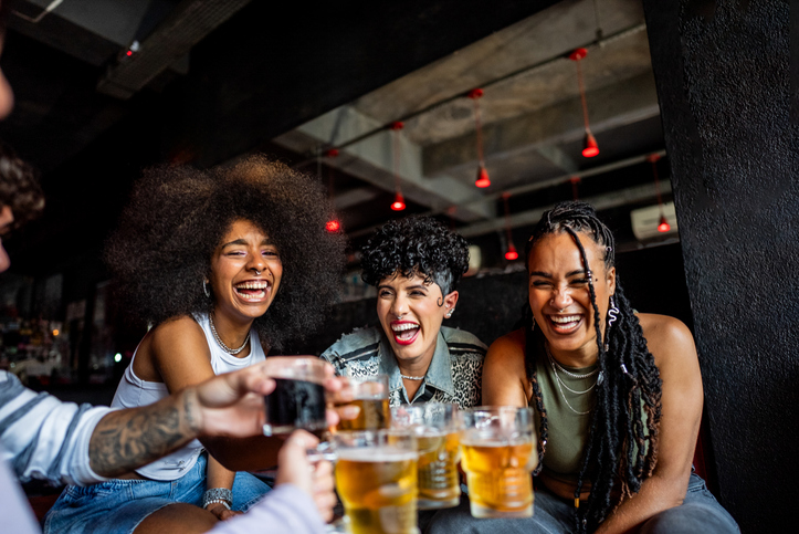 Friends talking and toasting beer at pub