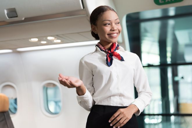 Black woman, Cabin crew or air hostess working in airplane. Female airline service agent working on plane with travel services smiling
