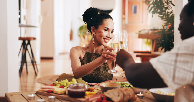 Cheers, champagne and couple on date with food to celebrate commitment, marriage and anniversary. Love, dating and man and woman with alcohol toast for romance, relationship and valentines day