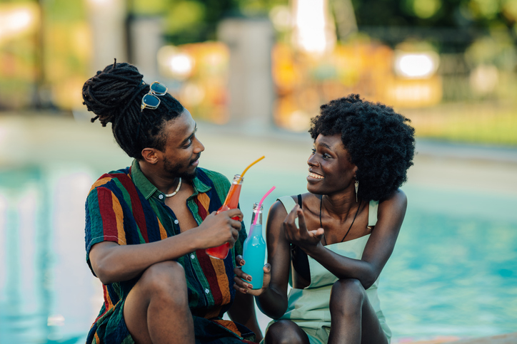 Young couple enjoying colorful drinks by the pool