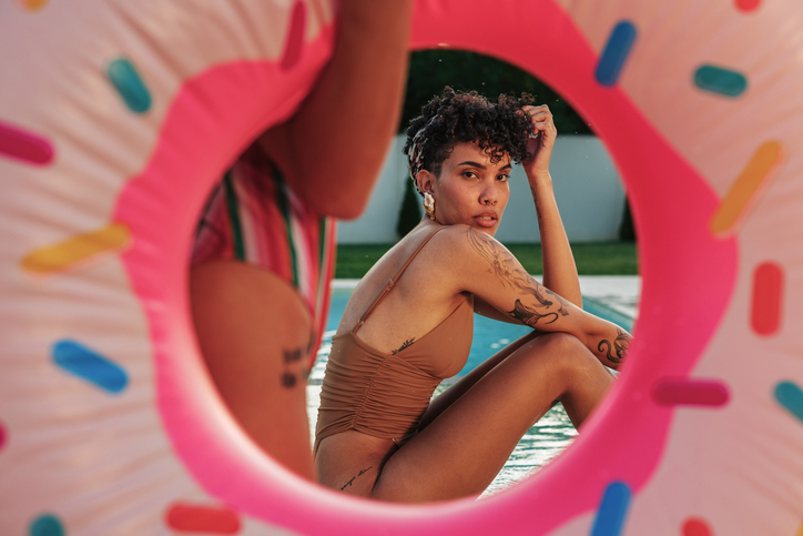 Young woman relaxing in a pool during summer vacation with friends