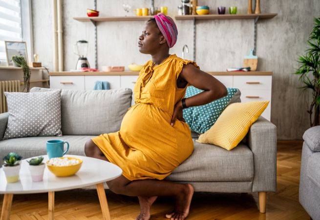 Pregnant woman experiencing back pain at home