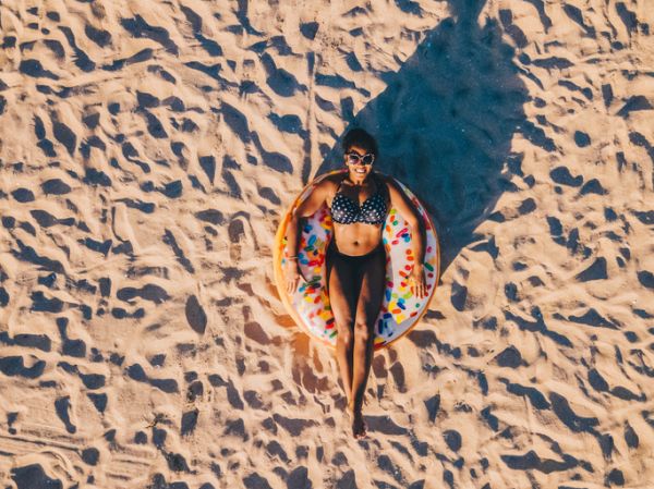 Relaxing woman sunbathing on a sandy beach from above