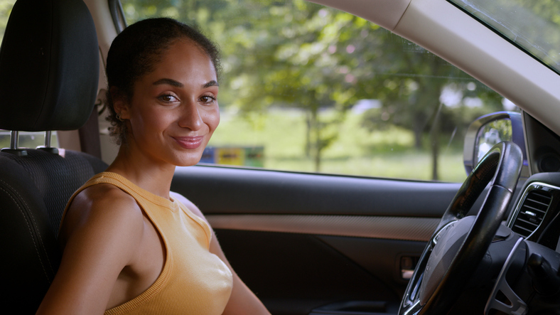 Happy successful African American woman female looking at camera businesswoman buyer new car owner auto automobile transport vehicle driver smile rent driving luxury electric employee business girl