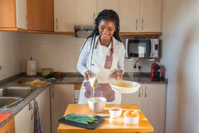 Smiling chef pouring hot soup into bowl in kitchen