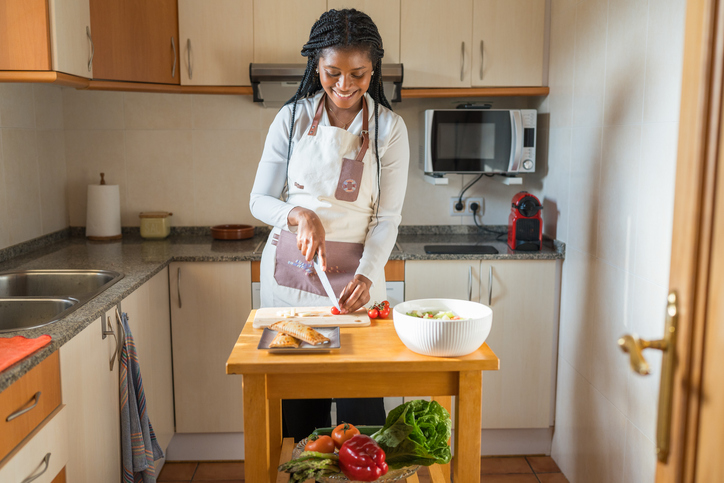 Young chef cutting tomatoes and preparing a healthy meal in her kitchen