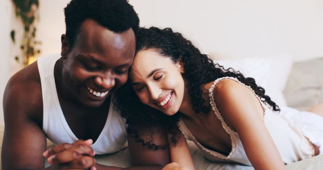 Happy, love and couple on bed laugh for relaxing, resting and bonding in hotel room. Marriage, relationship and black man and woman in bedroom for affection, commitment and talking on valentines day