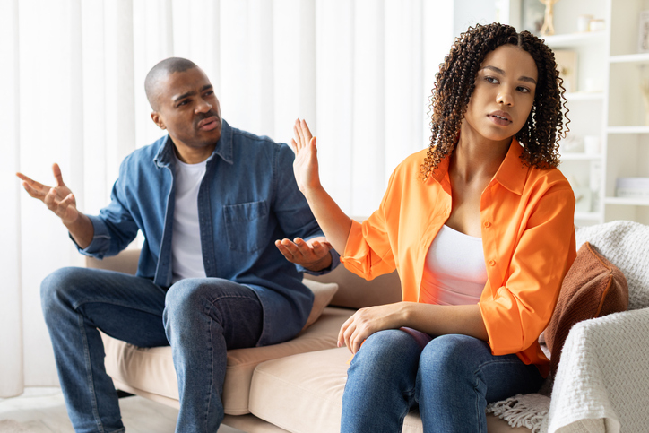 African American couple arguing at home, woman turning away with protest