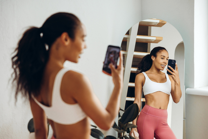 Smiling, fit African American woman wearing sportwear, bra and leggings taking picture
