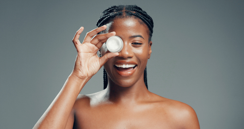 Skincare, lotion and portrait of black woman in studio for beauty, glow and self care cosmetics. Shine, dermatology and aesthetic with person and cream on gray background space for hydration product