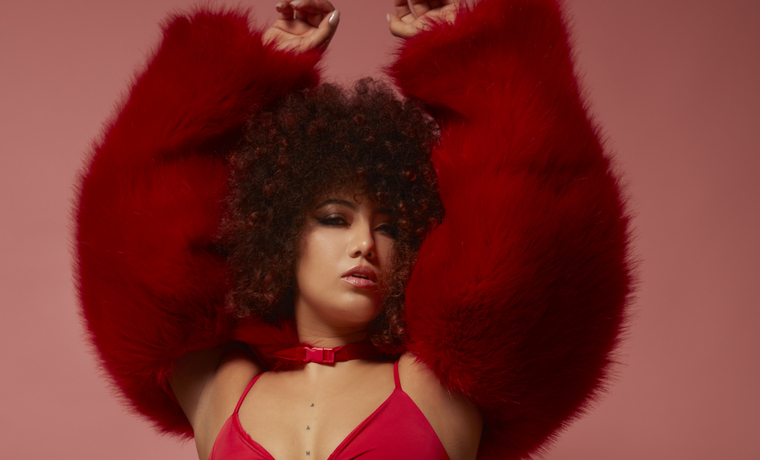 Curly-haired mixed race young woman in a red fur coat.