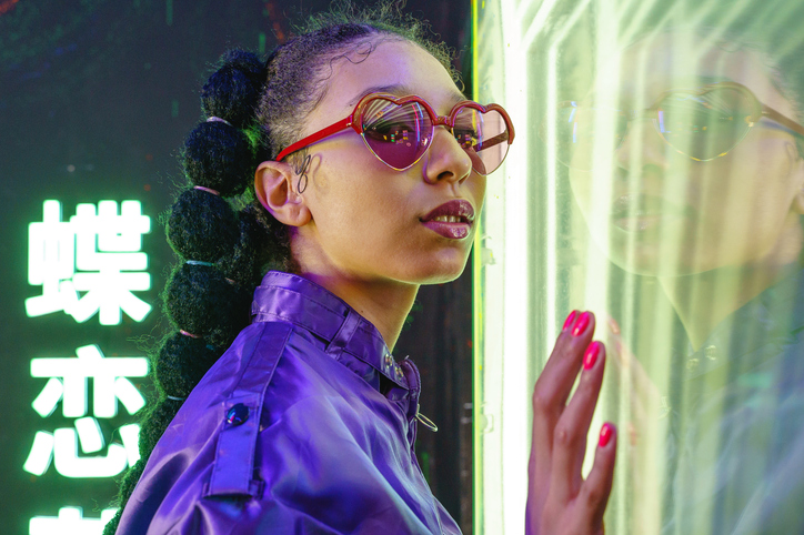 Fashion portrait of african woman with japanese neon lights looking at camera