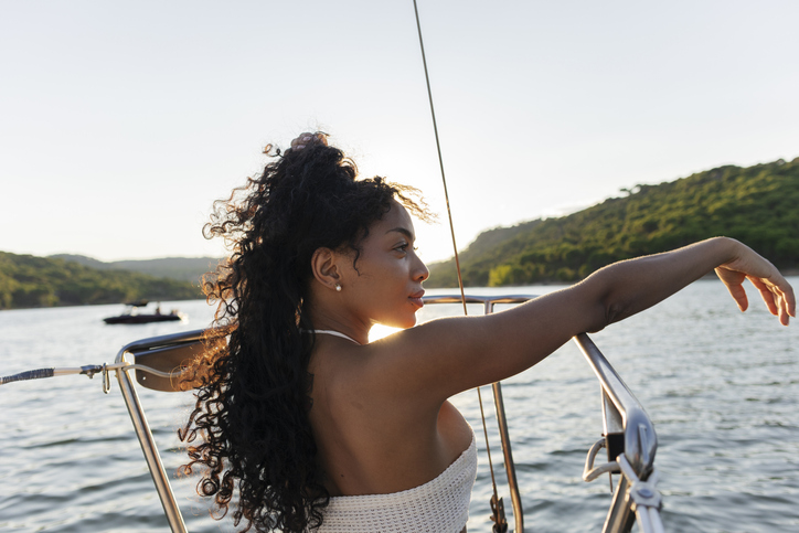 Young woman enjoying boat ride at sunset on lake